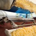 A stainless steel Super Air Knife with Plumbing Kit drying cheese during a shredding operation.